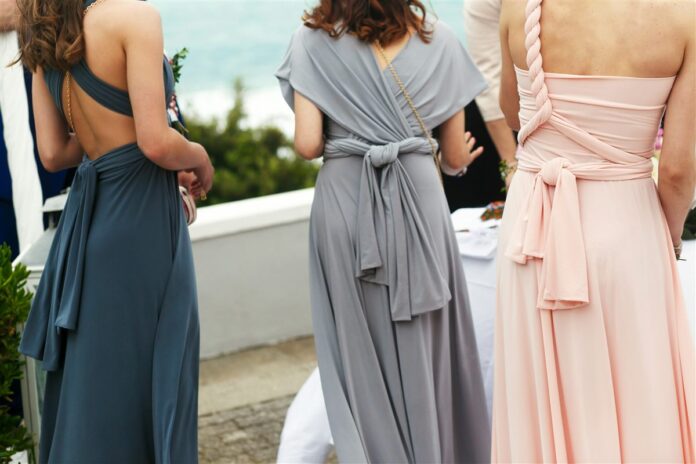 Three bridesmaids wearing different blue, grey and blush dress styles