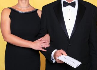 Two formally dressed guests holding an invitation