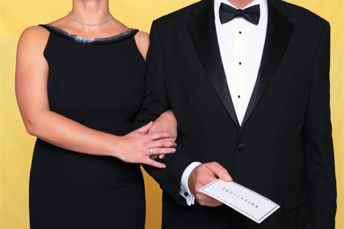 Two formally dressed guests holding an invitation