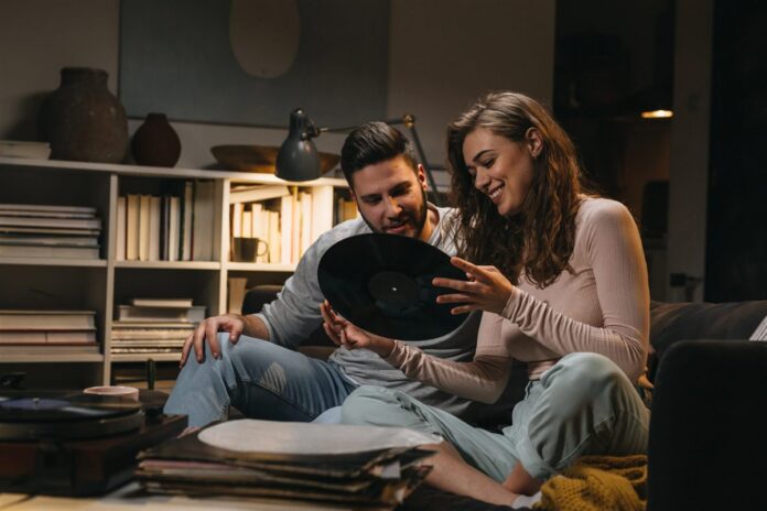 Couple choosing a vinyl record beside a record player at home